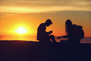 people playing music on the beach at sunrise